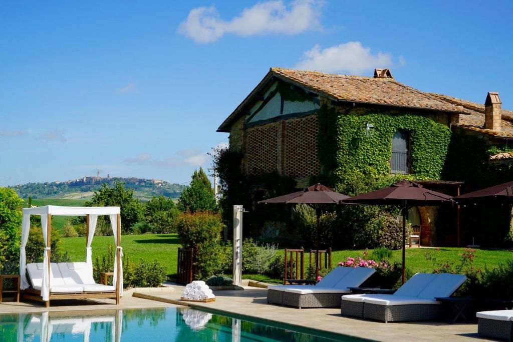 a house with a swimming pool with chairs and umbrellas at L'Olmo in Monticchiello