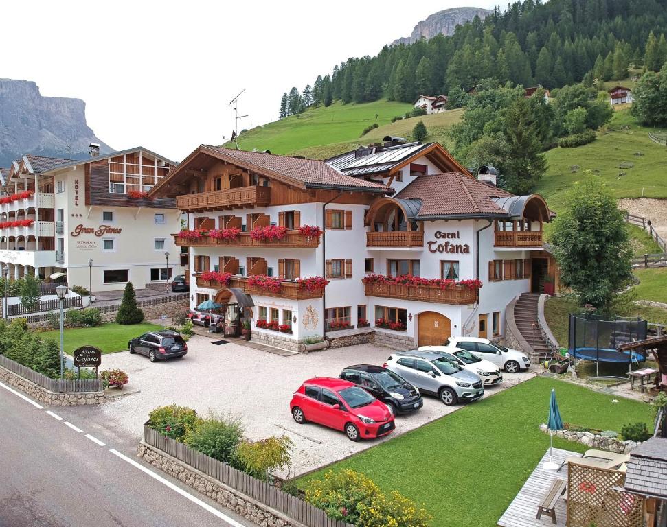 a hotel with cars parked in a parking lot at Garnì Tofana in Corvara in Badia