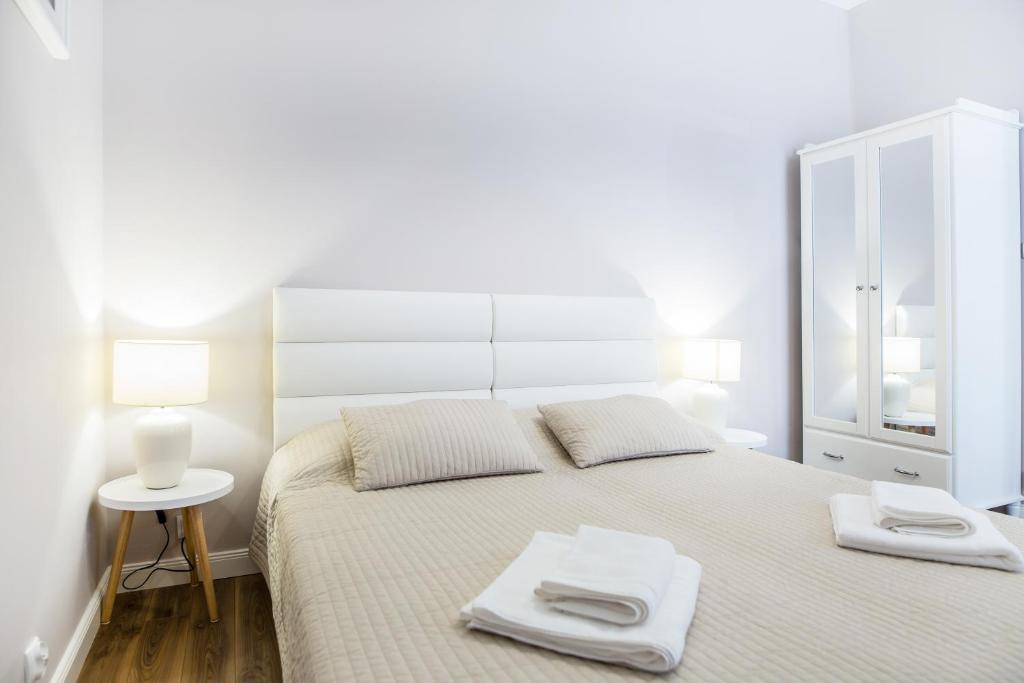 Bright bedroom with beige bed, mirrored wardrobe, bedside lamps and neatly folded towels.
