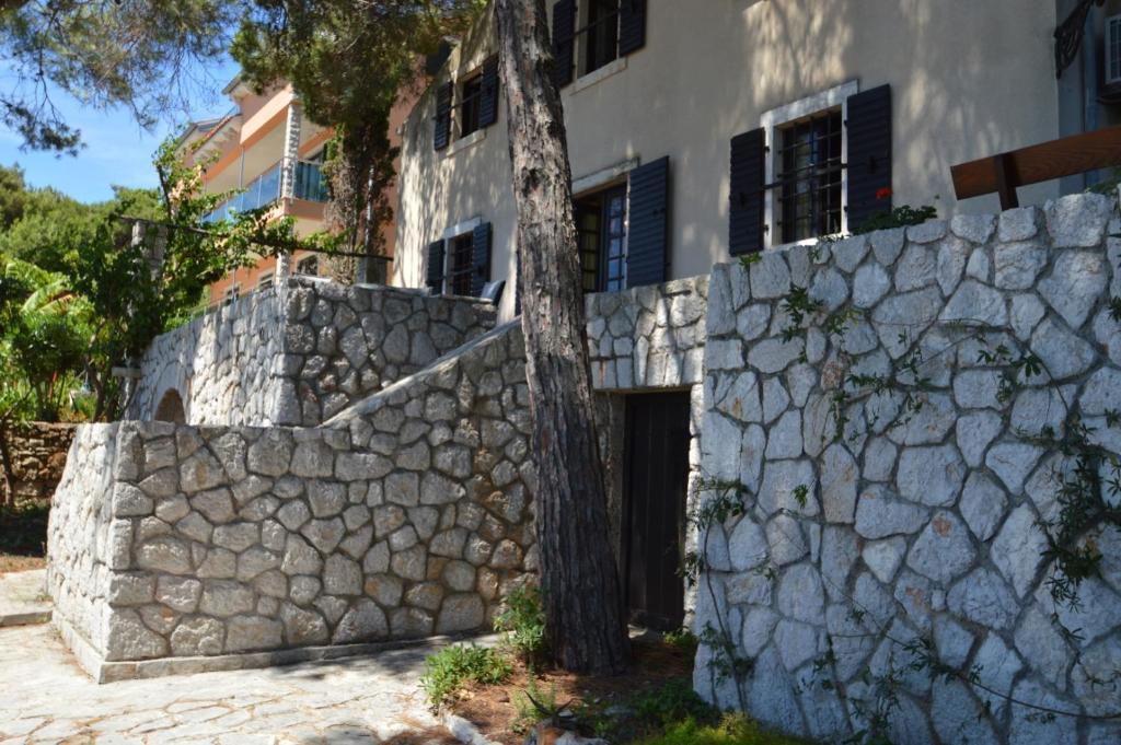 a stone wall with a tree in front of a building at Villa Avelina in Mali Lošinj