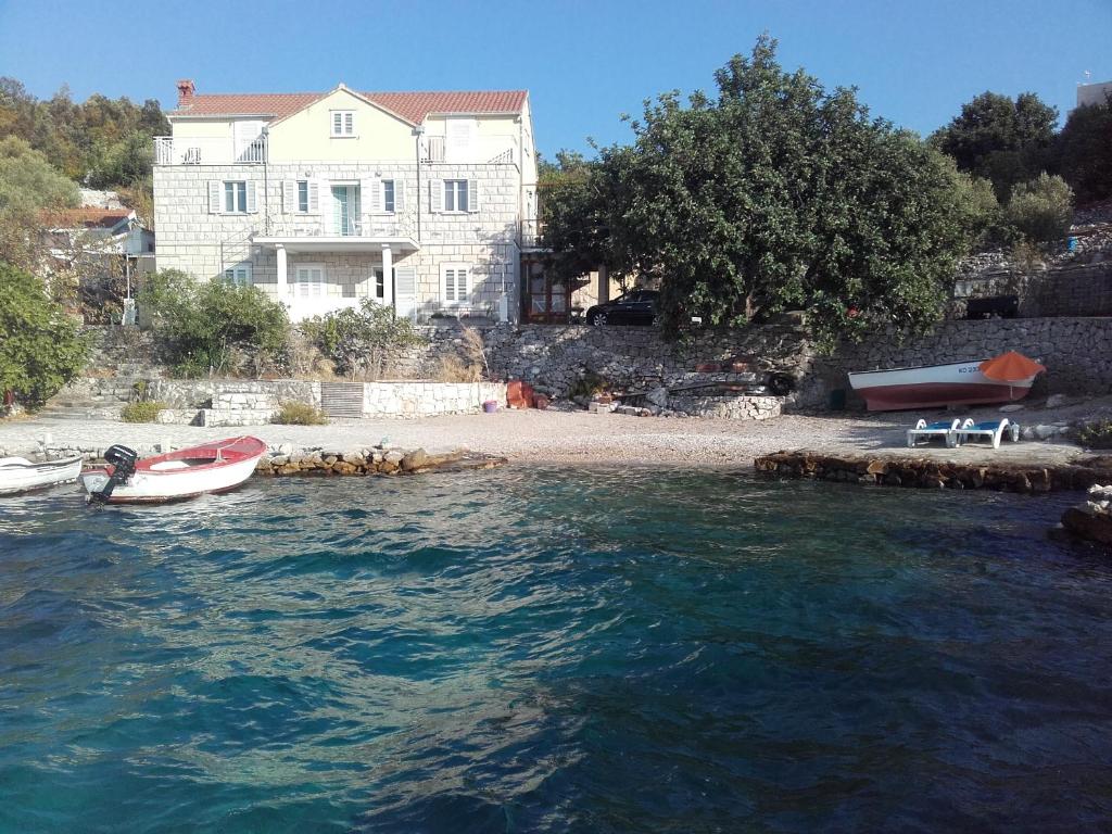 una casa e una piccola barca in acqua di I&J Relaxing Beach Apartments a Račišće