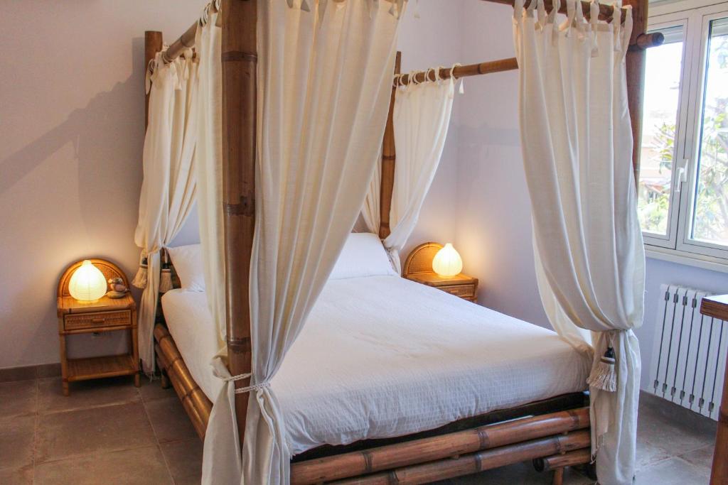 - une chambre avec un lit à baldaquin et des rideaux dans l'établissement Maison Tizi, à Passoscuro