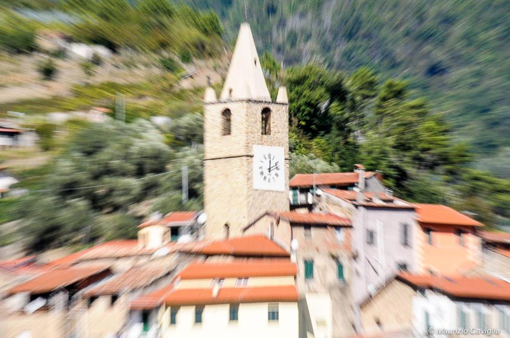 un edificio con una torre de reloj en la parte superior de los tejados en Teré Ceriana Affittacamere, en Ceriana