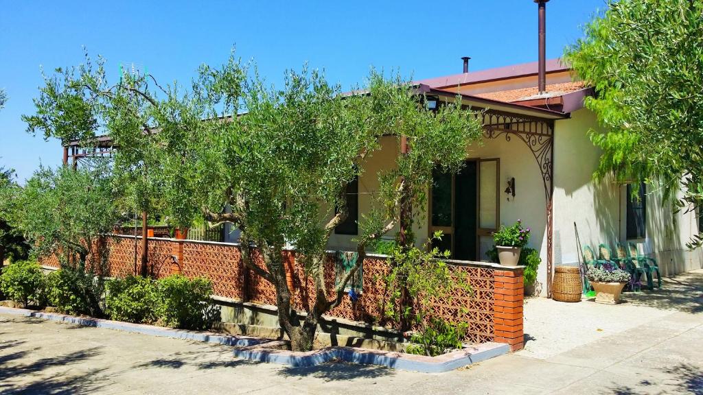 una casa con una valla de ladrillo y árboles delante de ella en The Sunset Home, en Piazza Armerina