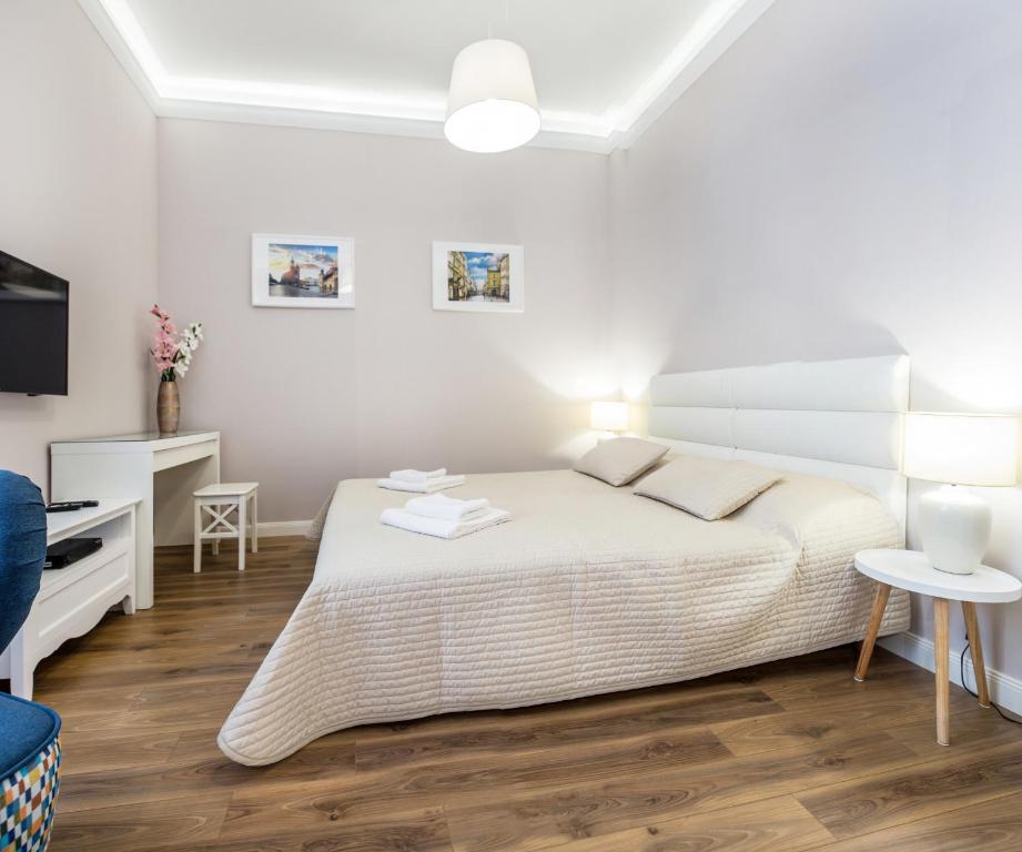 Cozy bedroom with large bed, desk, wall art, bedside lamps and patterned blue chair.