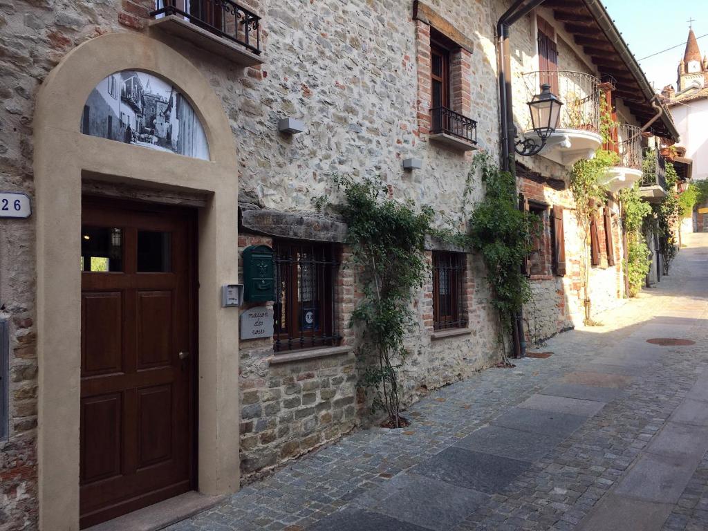 a stone building with a brown door on a street at Maison des Roses - Family Farm in Bossolasco