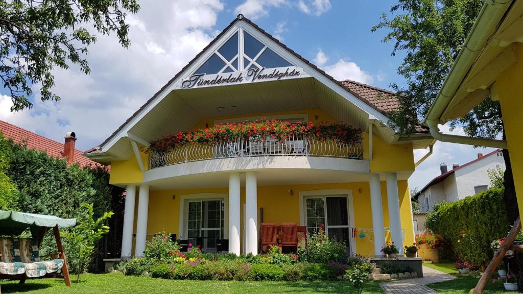 a yellow house with a balcony with flowers on it at Tündérlak Vendégház in Balatonfüred