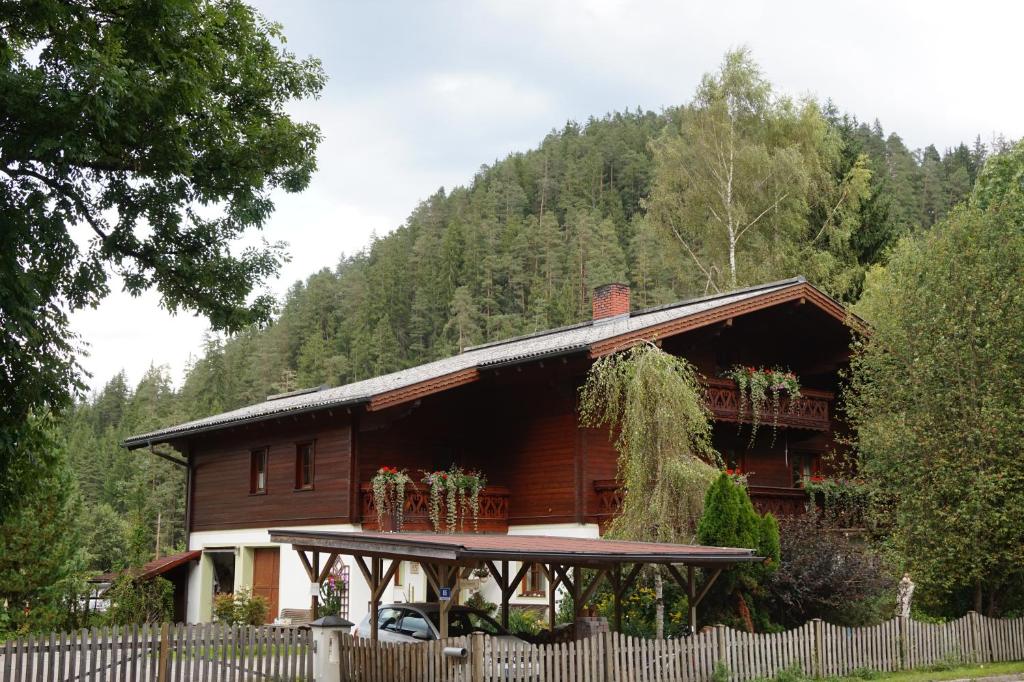 ein Holzhaus mit einem Zaun davor in der Unterkunft Appartements Huber in Altenmarkt im Pongau