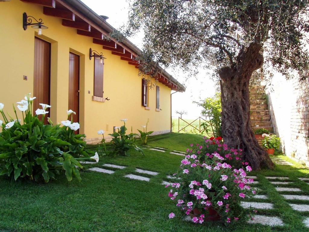una casa con un albero e fiori nel cortile di Agriturismo Tenuta Santa Maria a Notaresco