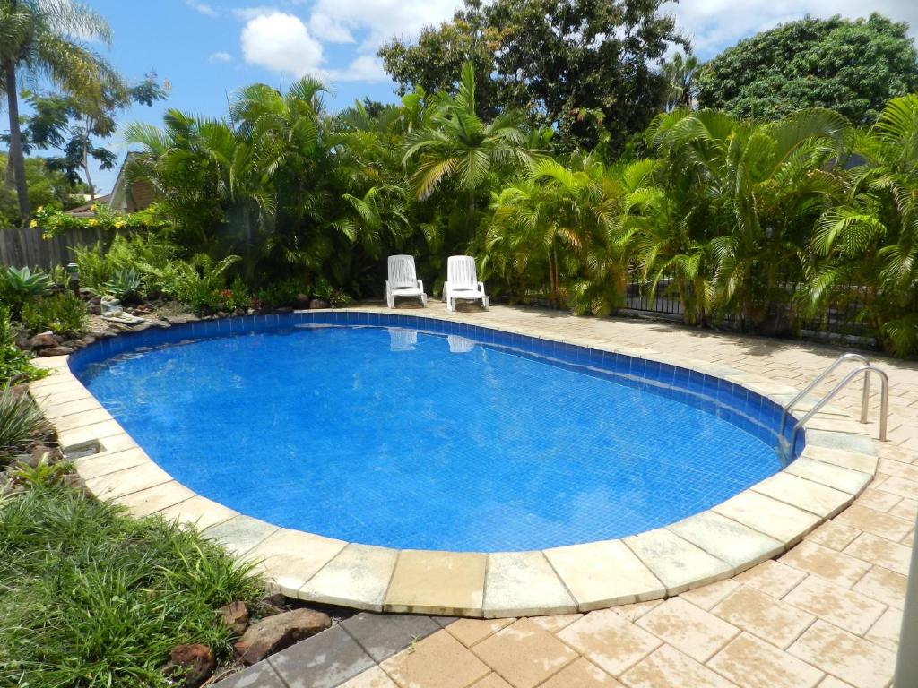 una gran piscina con 2 sillas en un patio en Golden Palms Motor Inn, en Bundaberg