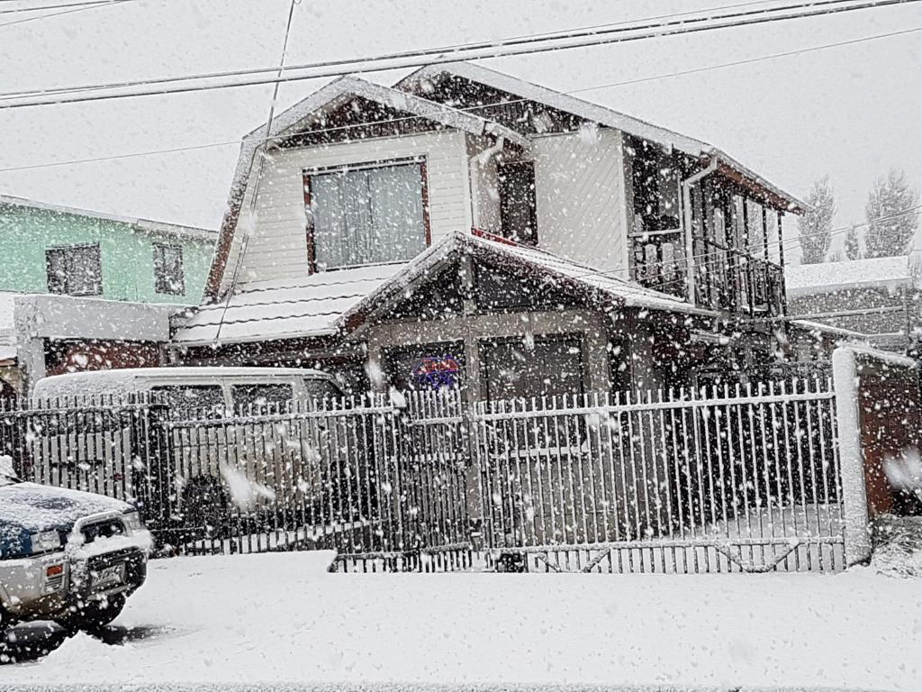 a house with a fence in the snow at La Casa Guesthouse in Punta Arenas
