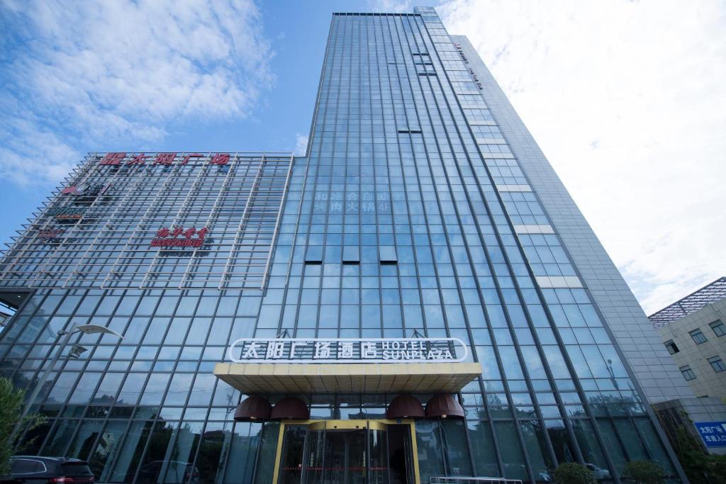 een hoog gebouw met een bord ervoor bij Suzhou Sun Plaza Hotel in Suzhou