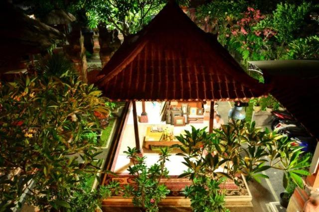 a small house with a straw roof and trees at Nyoman Murjana Homestay in Ubud