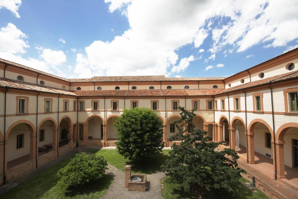 an exterior view of a building with trees in the courtyard at Antico Convento San Francesco in Bagnacavallo