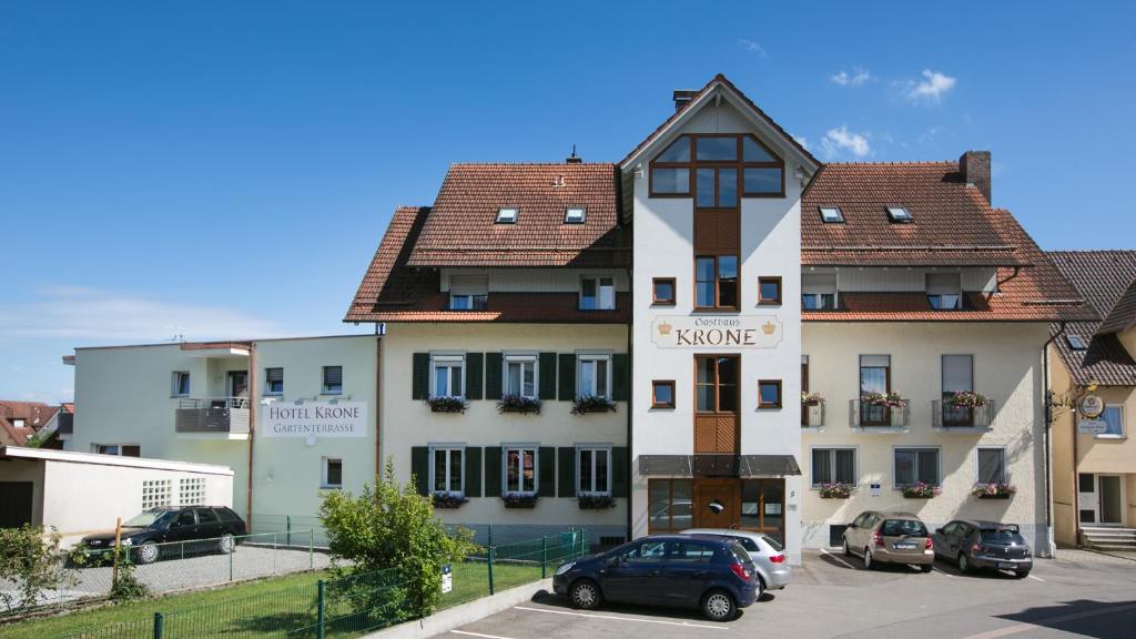 ein großes weißes Gebäude mit Autos auf einem Parkplatz in der Unterkunft Hotel Gasthaus Krone in Immenstaad am Bodensee