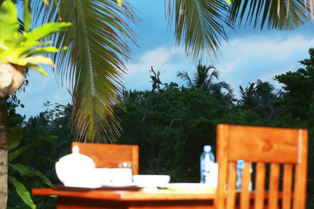 a table with two chairs and a palm tree at Villa Bird Gate in Galle