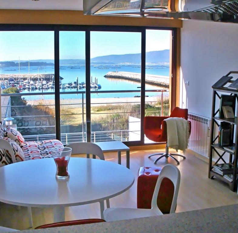 Habitación con mesas, sillas y vistas al océano. en Apartamentos Puerto Basella, en Villanueva de Arosa
