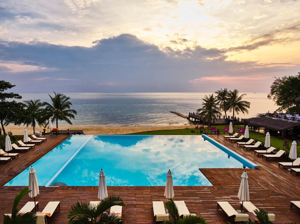 富國的住宿－富國島盛泰樂精選晨曦水療及度假村，一个带椅子的游泳池,背景是大海