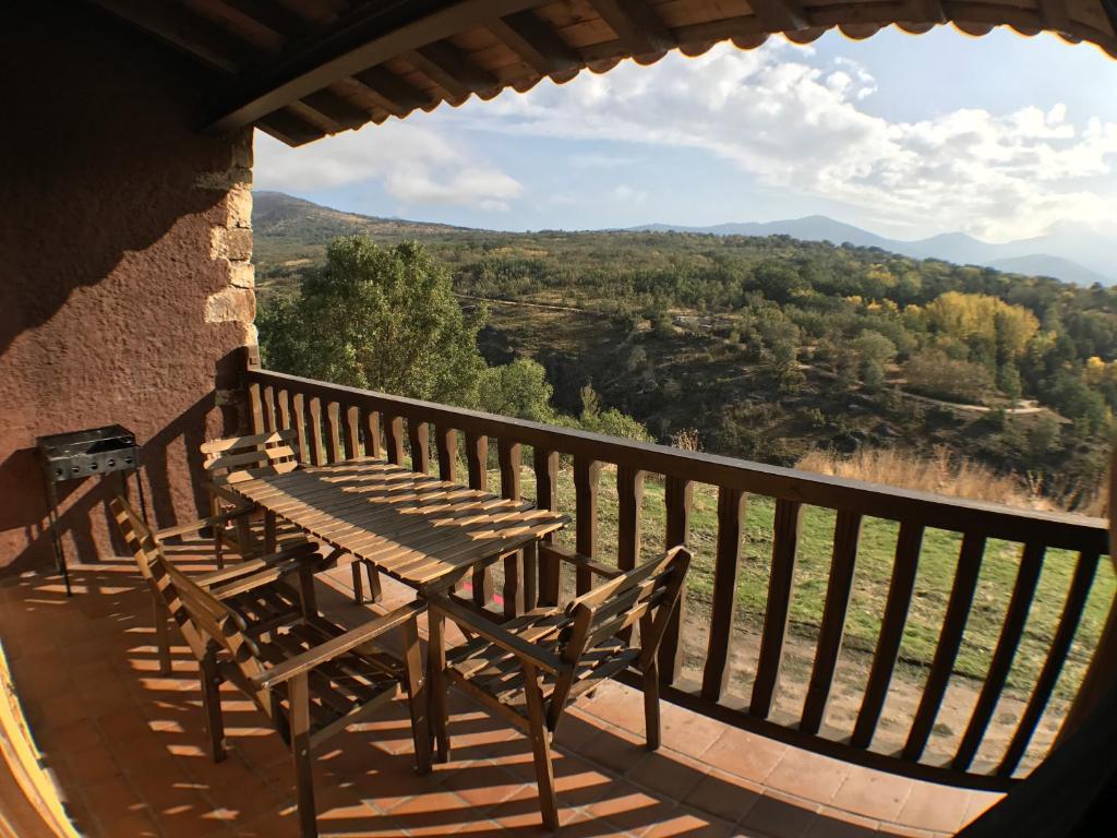una mesa de madera y un banco en un balcón con vistas en El Bulin de Horcajuelo, en Horcajuelo de la Sierra