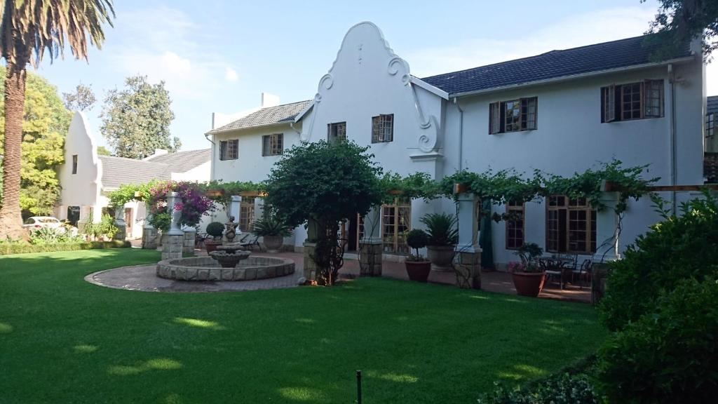 una casa blanca con un patio con césped verde en Le Chateau Guest House and Conference Centre, en Kempton Park