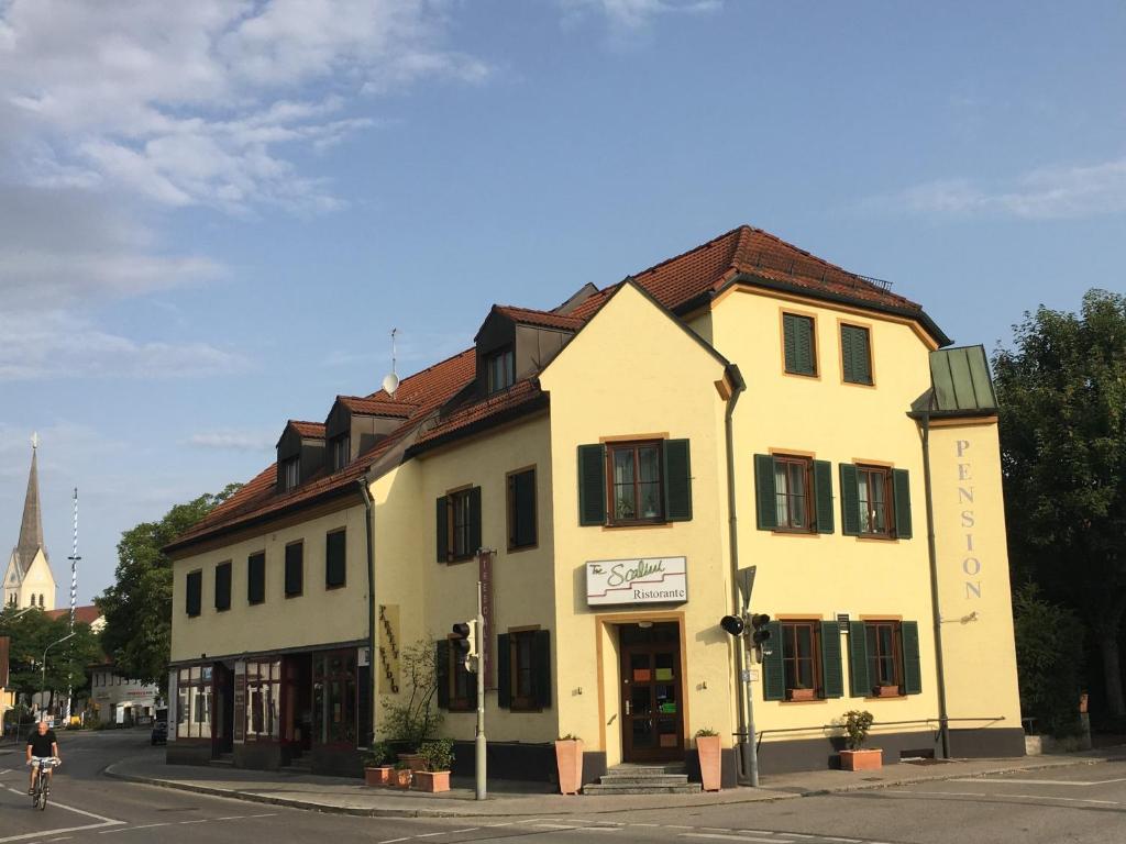 a yellow building on the corner of a street at Eberl Hotel Pension München Feldmoching in Munich