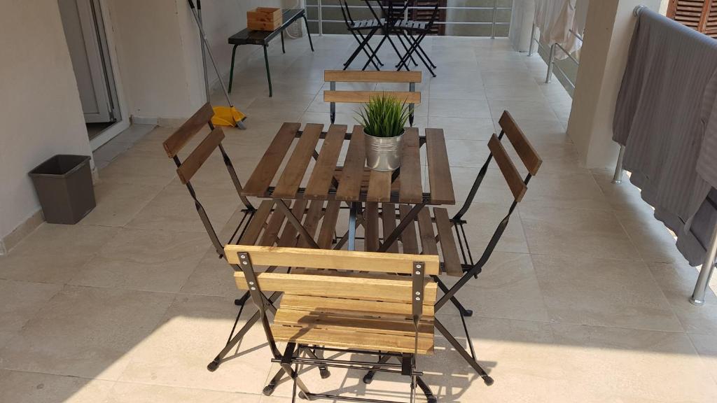 een houten tafel en stoelen met een plant erop bij IN Villa Guesthouse in Sutomore
