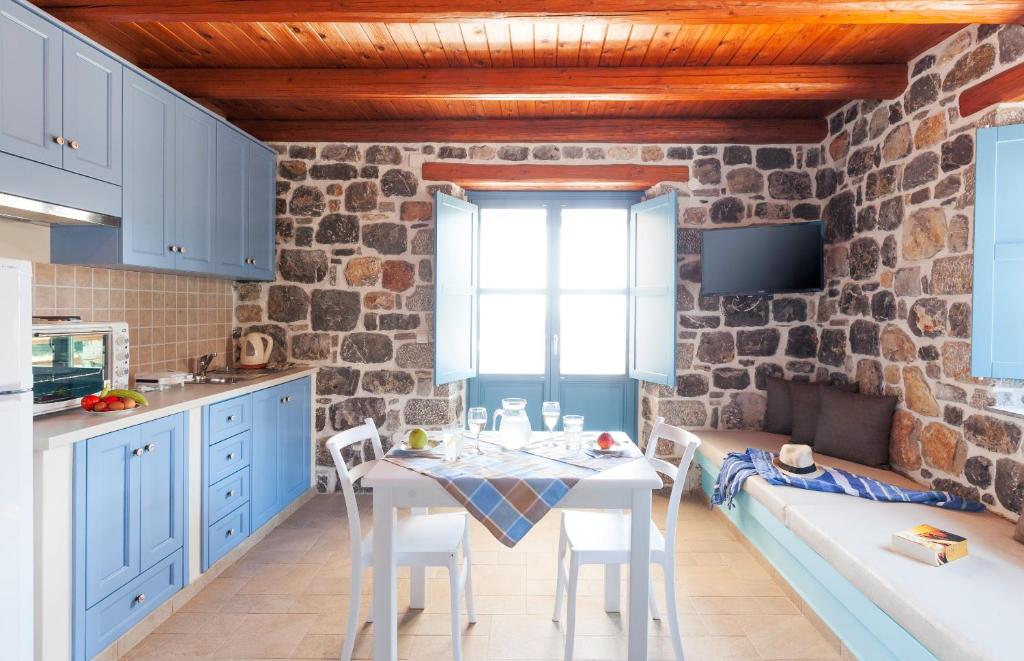 cocina con armarios azules, mesa y sillas en Pserimos Villas, en Psérimos