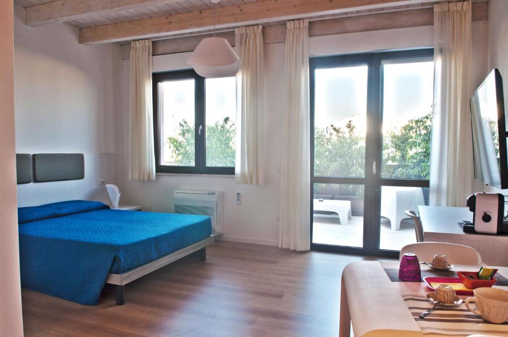a bedroom with a blue bed and a large window at Four Rooms Guesthouse in Oristano