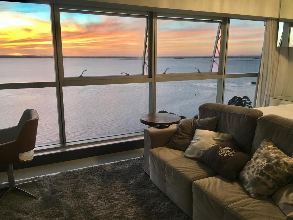 a living room with a couch and a view of the ocean at Loft Barra in Porto Alegre