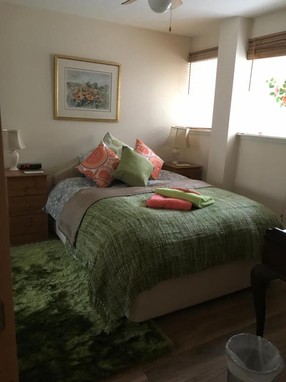 a bedroom with a bed with a green blanket and pillows at City Centre Executive Apartment - Private Parking, Gym & Sauna in Aberdeen