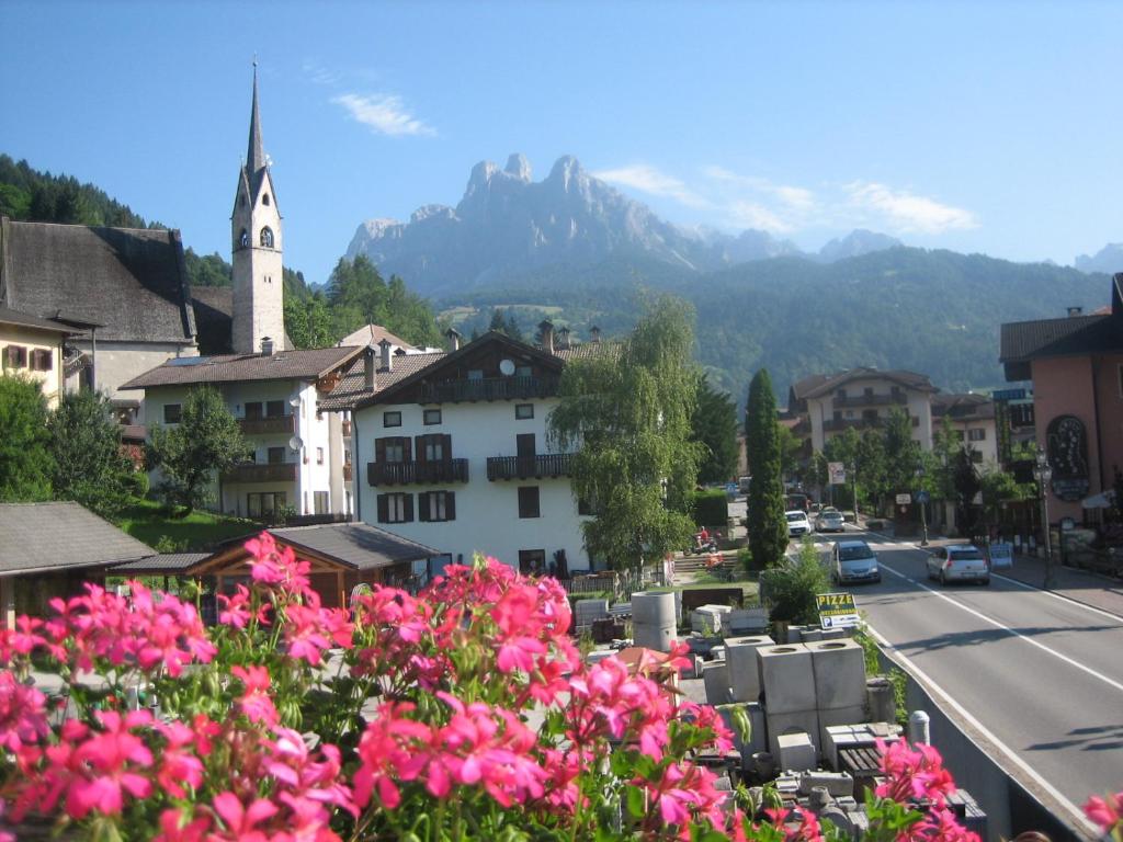 a town with a mountain in the background with pink flowers at Casa Caterina in Fiera di Primiero