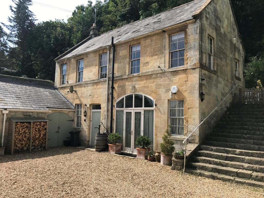 ein altes Steingebäude mit einer Treppe und einer Garage in der Unterkunft Berkeley Coach House, near Bath in Bath