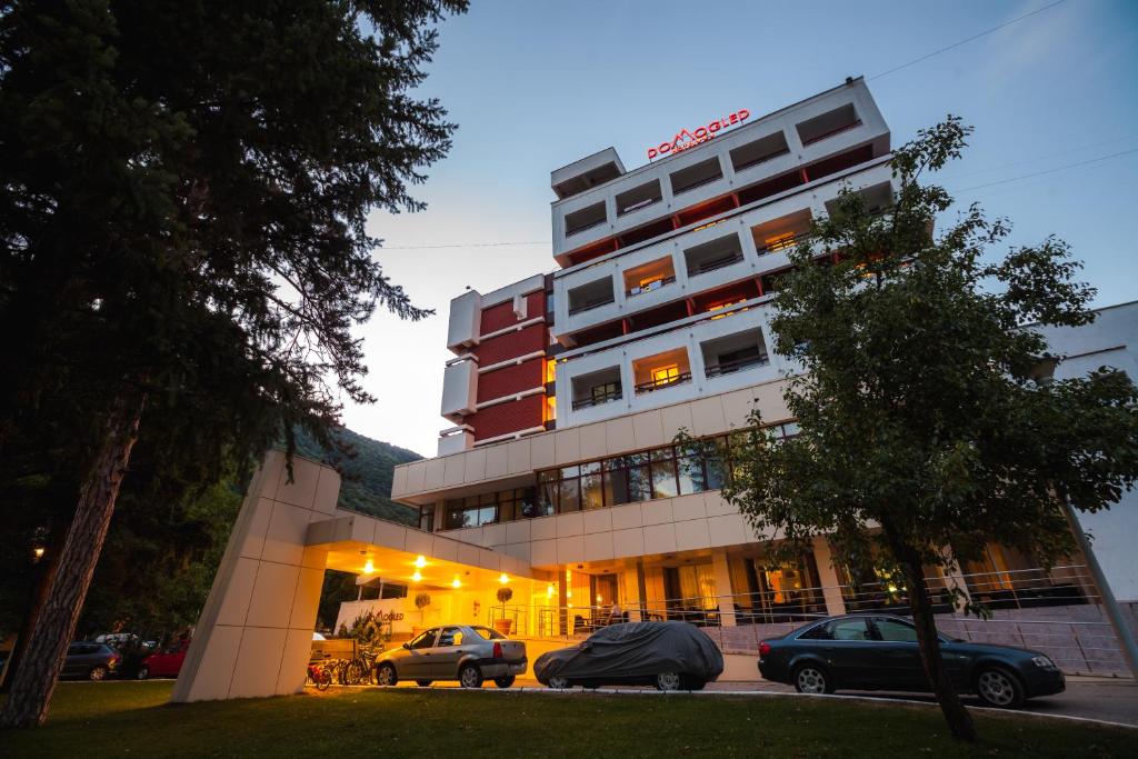 un edificio con coches estacionados frente a él en Hotel Domogled, en Băile Herculane