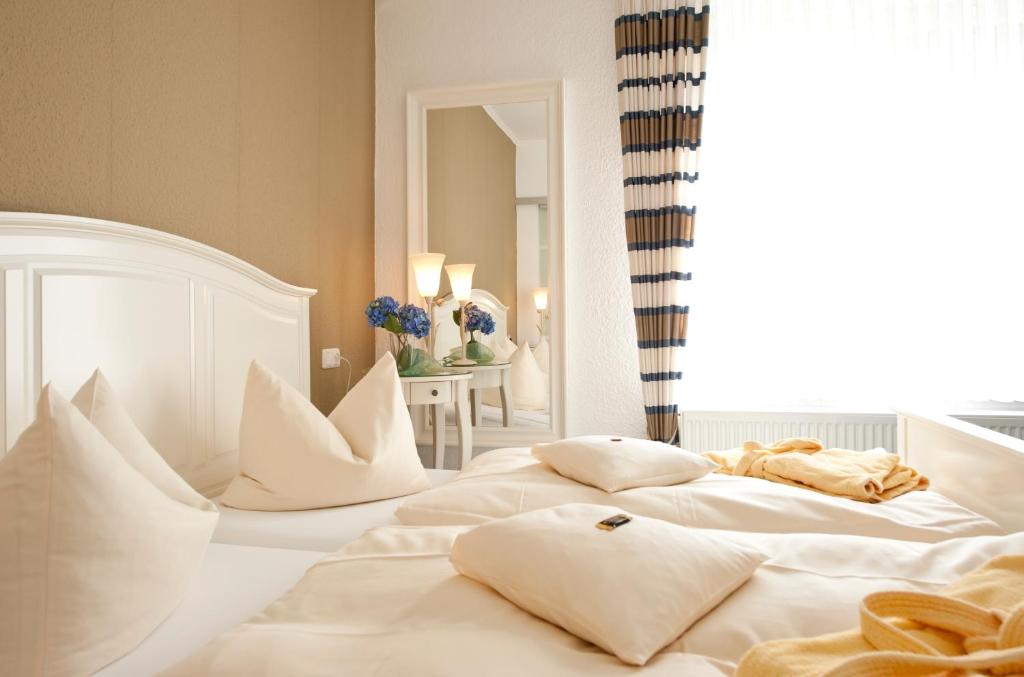a bedroom with two white beds with pillows at Boutiquehotel Das Haus am Walde in Bad Bevensen