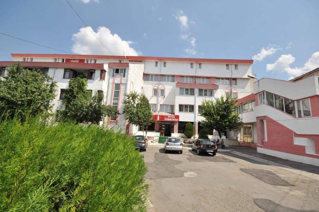 Hotel Dobrogea في كونستانتا: مبنى فيه سيارات متوقفة في موقف للسيارات