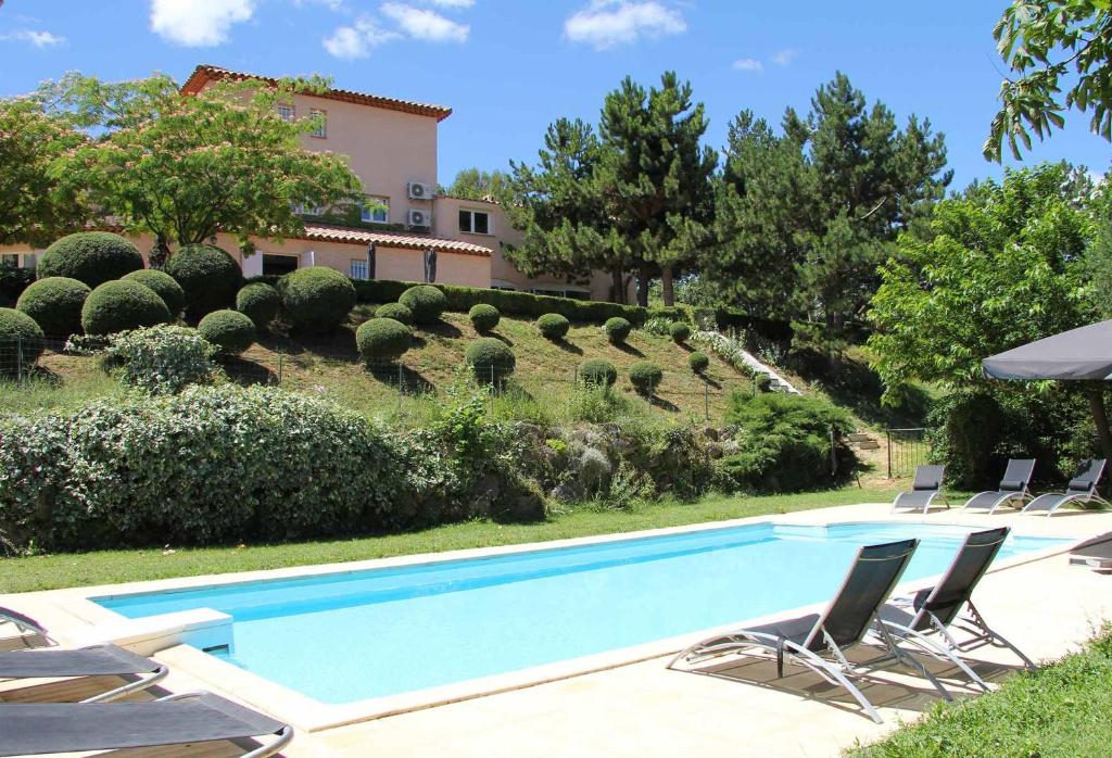 a swimming pool in a yard with chairs and a house at Le Jardin de Celina in Valensole