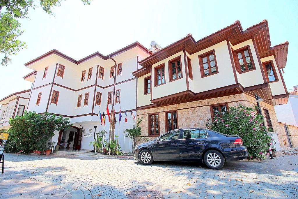 un'auto parcheggiata di fronte a un grande edificio di Hotel Karyatit Kaleici a Antalya (Adalia)