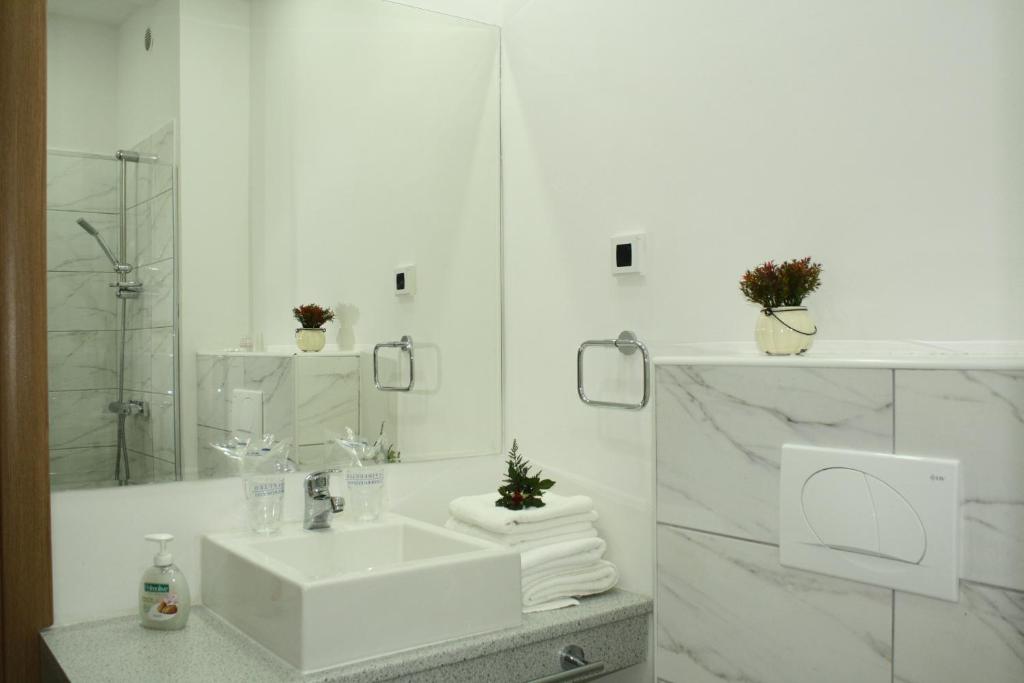a white bathroom with a sink and a mirror at Hotel Danica in Petrovac na Moru