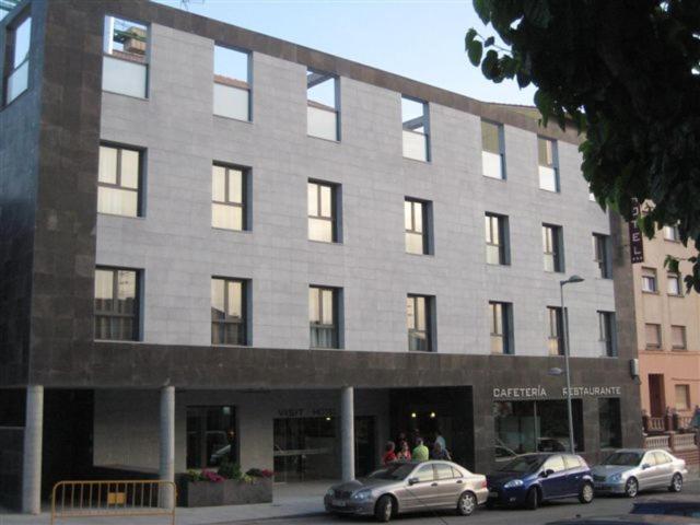 un gran edificio con coches estacionados frente a él en Visit Hotel en Caspe