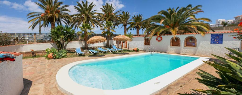 una piscina con palmeras y un edificio en Finca el Castillo en Buenavista del Norte