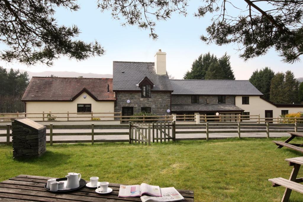 a house with a fence and a table in front of it at Vulcan Lodge Cottages in Rhayader