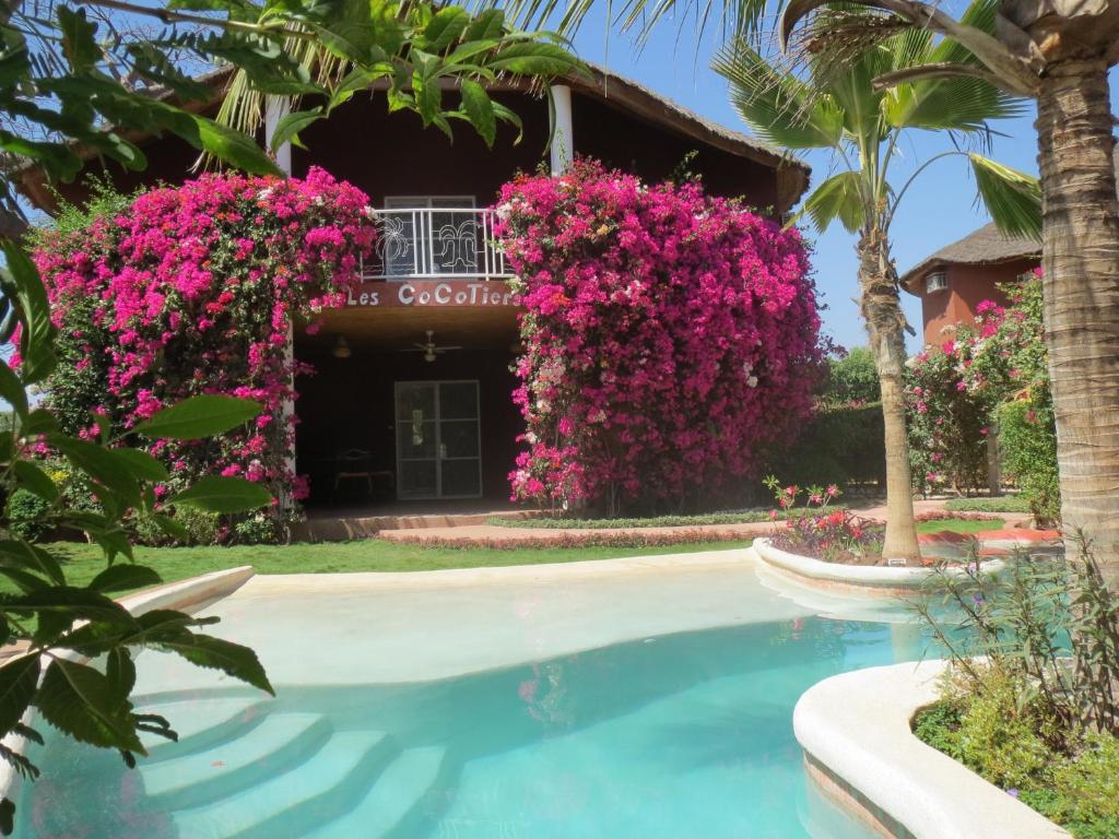 um resort com flores cor-de-rosa e uma piscina em Villa Les CoCotiers em Saly Portudal