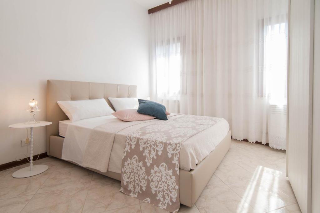 biała sypialnia z dużym łóżkiem z białymi zasłonami w obiekcie Riva Excelsior Apartment w Wenecji