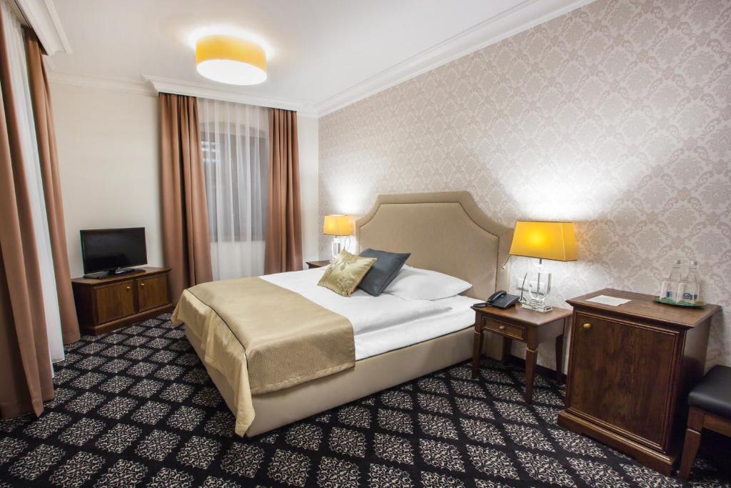 pokój hotelowy z łóżkiem, dwoma stołami i telewizorem w obiekcie HG Hotel w mieście Toszek
