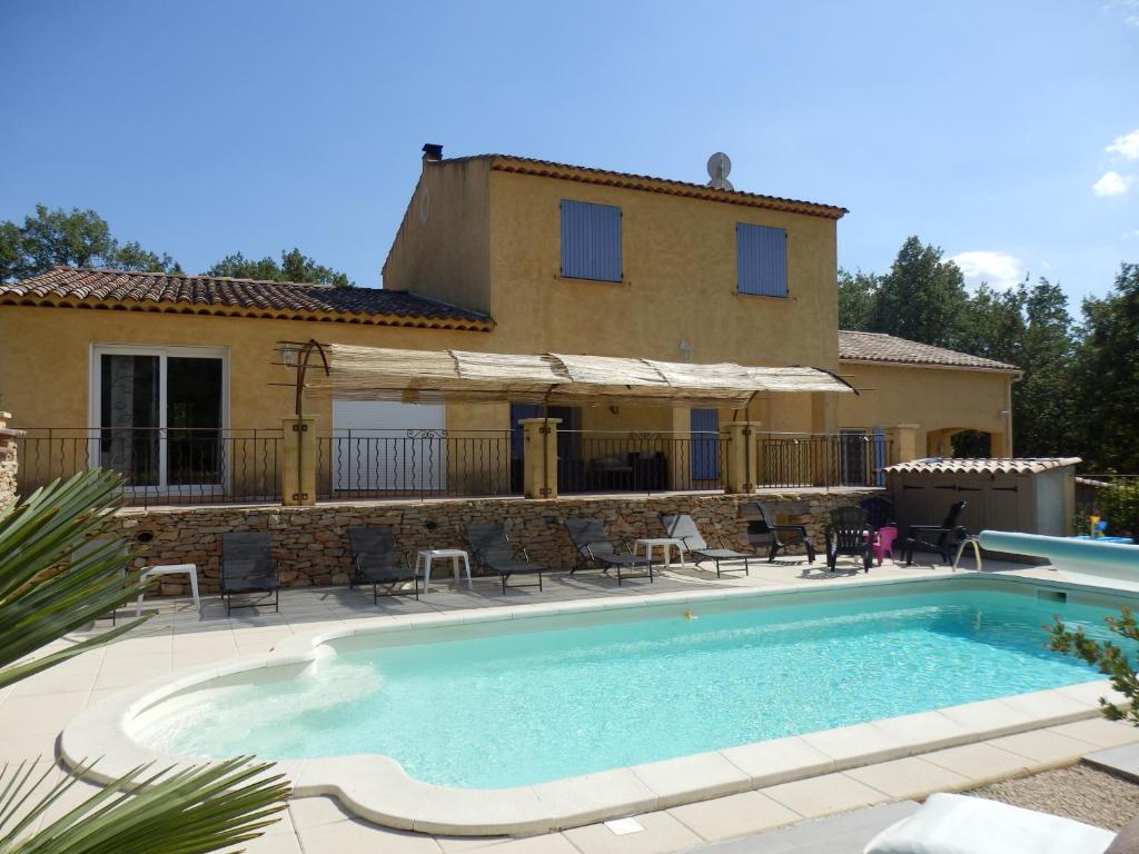 a villa with a swimming pool in front of a house at Gîte des lavandes in Montagnac