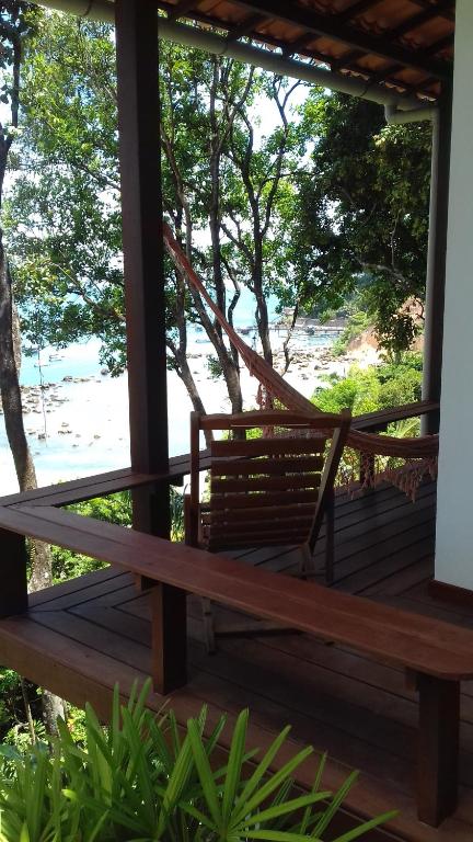 a bench on a porch with a view of the beach at Casa Shuhari in Morro de São Paulo