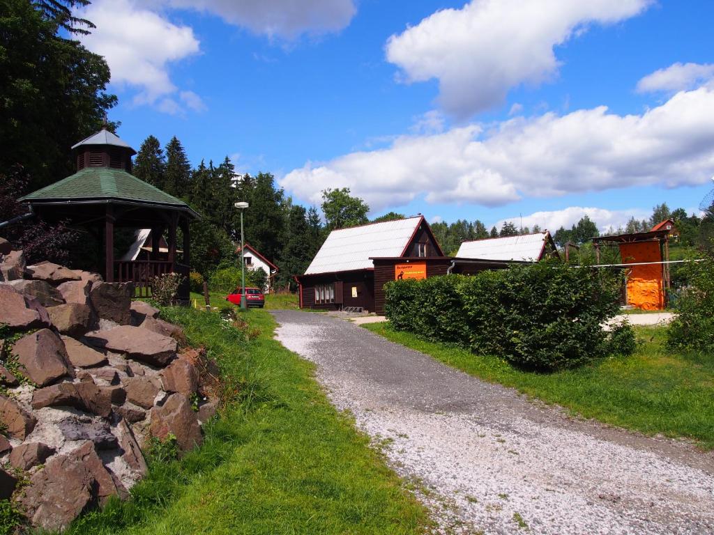 a gravel road next to a building and a stone wall at Kemp Prachovská osma in Libuň