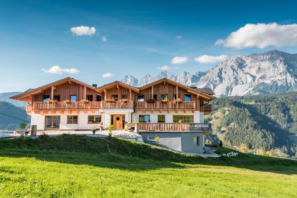 a house on a hill with mountains in the background at LA MONTANA - Ski & Hiking LODGE in Schladming