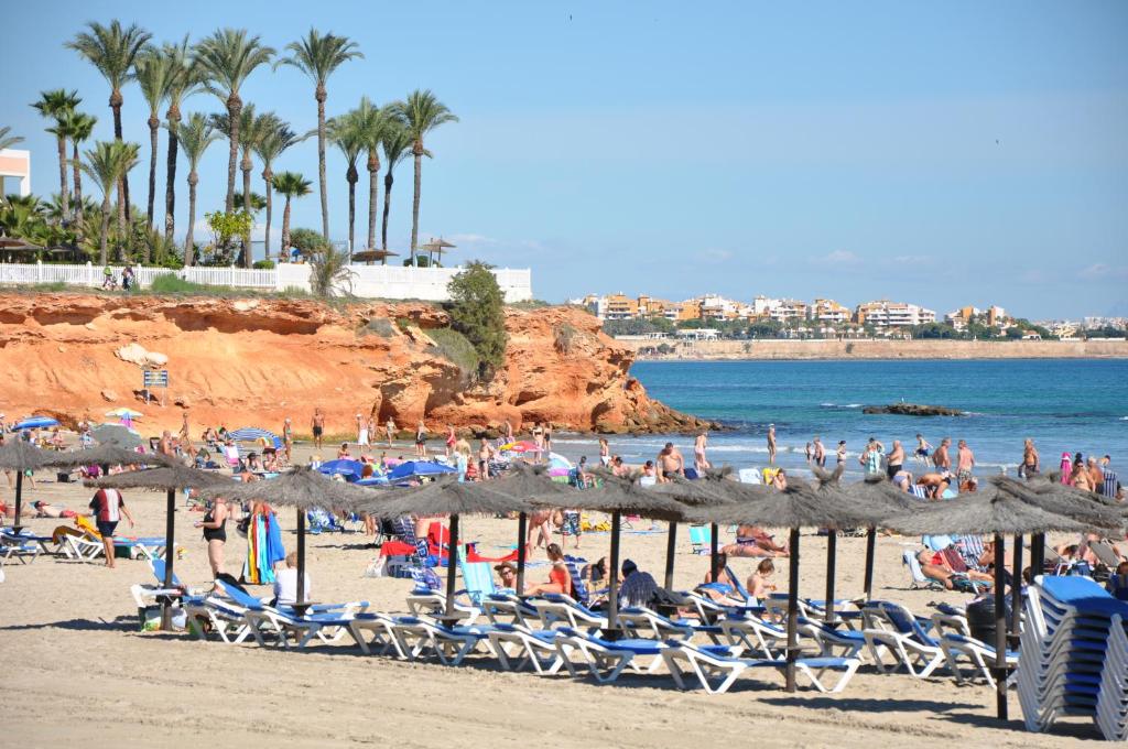 un grupo de personas en una playa con sillas y sombrillas en Apartament Margarita Cabo Roig "Ozonizado", en Cabo Roig