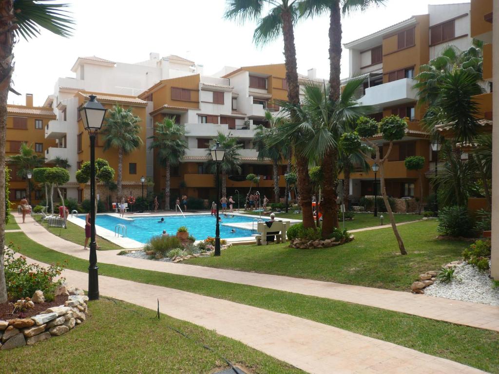 a resort with a swimming pool and palm trees at La Recoleta Punta Prima in Torrevieja